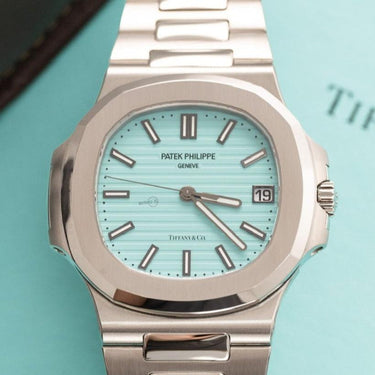 Tiffany Patek Philippe Nautilus laid on the Tiffany Box, displayed below the Patek leather watch case.